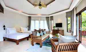 Et lyst og rummeligt hotelværelse med to enkeltsenge, træmøbler og store vinduer med udsigt til en frodig altan. (AI-genereret tekst)