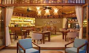 Interiør af en hyggelig restaurant med træindretning, borde og stole samt dekorative lamper. (AI-genereret tekst)