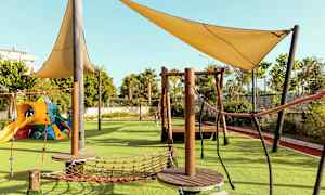 Legeplads med klatrestativer og skyggefulde sejl. (AI-genereret tekst)
