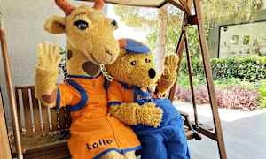 To figurer i kostumer, en giraf og en bjørn, sidder på en gynge og vinker. (AI-genereret tekst)