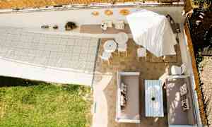 Udsigt over en terrasse med siddeområder, borde, parasol og græsplæne. (AI-genereret tekst)