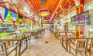 Restaurant med træborde og stole samt farverige flag hængende fra loftet. (AI-genereret tekst)