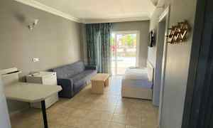 Et hotelværelse med sofa, bord og seng samt udsigt til en balkon. (AI-genereret tekst)