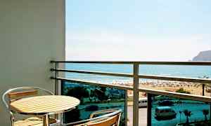 Altan med et bord og to stole, udsigt over stranden og havet. (AI-genereret tekst)