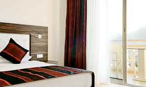 Hotelværelse med enkeltseng og balkon med udsigt. (AI-genereret tekst)