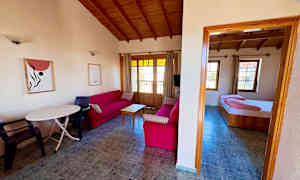 Stue med røde sofaer og trægulv samt et tilknyttet soveværelse. (AI-genereret tekst)