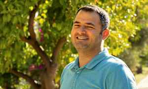 En person i en blå skjorte står foran en frodig have. (AI-genereret tekst)