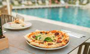 En pizza på et bord ved en pool. (AI-genereret tekst)