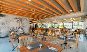 En moderne restaurant med store vinduer, træmøbler og dekorative loftsbjælker. (AI-genereret tekst)