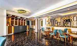 Lobby med reception, blå og gule stole samt moderne indretning. (AI-genereret tekst)