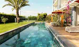 En lang smal pool omgivet af grønne områder og en moderne bolig. (AI-genereret tekst)