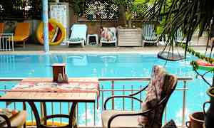 En swimmingpool med liggestole og en siddegruppe i forgrunden. (AI-genereret tekst)