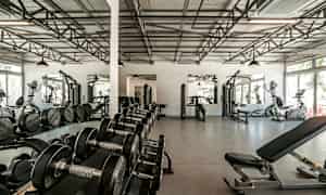 Træningscenter med fitnessmaskiner, håndvægte og spejle. (AI-genereret tekst)