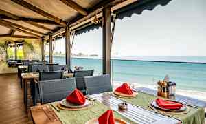 Restaurant med havudsigt, borde med røde servietter. (AI-genereret tekst)