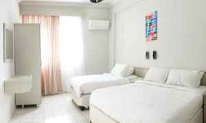 Et lyst hotelværelse med to senge, et vindue med gardiner og et skab. (AI-genereret tekst)