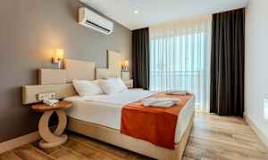 Et hotelværelse med en stor seng, sidebord og vindue med mørklægningsgardiner. (AI-genereret tekst)