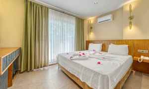 Hotelværelse med en dobbeltseng redt med hvide lagner og dekoreret med blomster. (AI-genereret tekst)