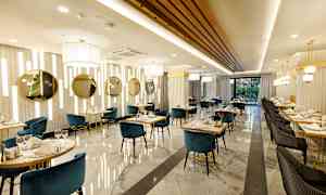 Billede af en elegant restaurant med blå og sorte stole, marmorgulv og gulddetaljer. (AI-genereret tekst)