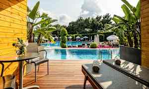 Terrasse foran en pool med liggestole, bord og planter. (AI-genereret tekst)