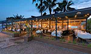 En restaurant ved stranden med hvide duge om aftenen. (AI-genereret tekst)