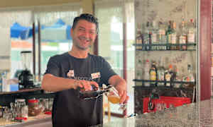 En bartender hælder en drink op ved en bar. (AI-genereret tekst)