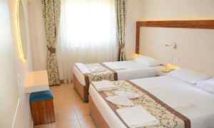 Hotelværelse med to enkeltsenge, lyse gardiner og et spejl. (AI-genereret tekst)