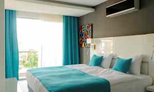 Moderne hotelværelse med en dobbeltseng, hvide og turkise farver. (AI-genereret tekst)