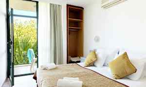 Et hotelværelse med en redt seng, åbent skab og en altandør, der fører ud til en terrasse. (AI-genereret tekst)