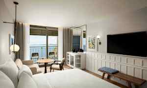 Hotelværelse med havudsigt gennem en altandør. (AI-genereret tekst)