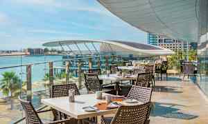 Udendørs servering med opdækkede borde og havudsigt. (AI-genereret tekst)