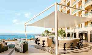 En udendørsbar med siddeområde, parasol og udsigt over havet. (AI-genereret tekst)