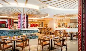 Interiør af en farverig og stilfuld restaurant med træborde og stole. (AI-genereret tekst)