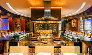 Interiør af en restaurant med åben køkkenlayout og siddepladser rundt omkring. (AI-genereret tekst)