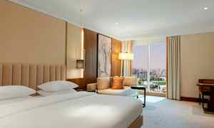 Et hotelværelse med en dobbeltseng, siddegruppe og et stort vindue med udsigt over byen. (AI-genereret tekst)