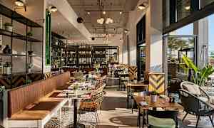 Moderne indrettet restaurant med store vinduer og siddepladser. (AI-genereret tekst)