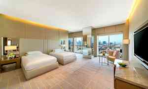 To enkeltsenge i et moderne hotelværelse med store vinduer og udsigt over byen. (AI-genereret tekst)