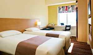 Et hotelværelse med to enkeltsenge, en arbejdsstation ved et vindue og moderne møbler. (AI-genereret tekst)