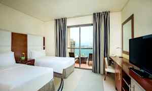 Hotelværelse med to enkeltsenge, balkon med udsigt over havet. (AI-genereret tekst)