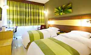 Et hotelværelse med to enkelt-senge, skjult belysning ved sengegavle, et skrivebord og grønne gardiner, der komplementerer værelsets indretning. (AI-genereret tekst)