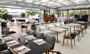 En elegant restaurant med borde og siddepladser, dekoreret med planter og moderne interiør. (AI-genereret tekst)