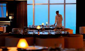 En restaurant med elegant dækkede borde og store vinduer med udsigt. (AI-genereret tekst)