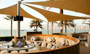 En siddeområde med skygge og udsigt over havet. (AI-genereret tekst)