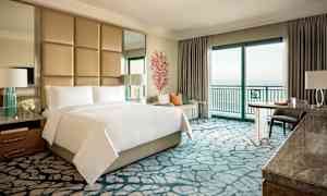 Et luksuriøst hotelværelse med dobbeltseng, siddeområde og havudsigt. (AI-genereret tekst)