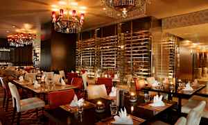 En elegant restaurant med dækkede borde, polstrede stole og lysekroner i loftet. (AI-genereret tekst)