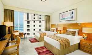 Hotelværelse med to enkeltsenge, skrivebord og store vinduer. (AI-genereret tekst)