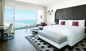 Lyst og moderne hotelværelse med en stor dobbeltseng og adgang til balkon med havudsigt. (AI-genereret tekst)