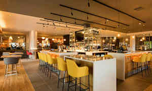 En bar med moderne møbler og en velassorteret hylde med flasker. (AI-genereret tekst)