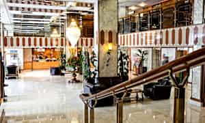 En hotellobby med marmorgulv, en receptionsdisk i baggrunden og siddepladser. (AI-genereret tekst)