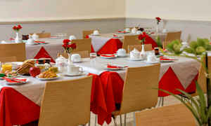 Et rum med dækkede borde, røde og hvide duge og tallerkener med morgenmad. (AI-genereret tekst)