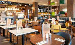 Restaurant med flere spiseborde og stole i forskellige farver. (AI-genereret tekst)